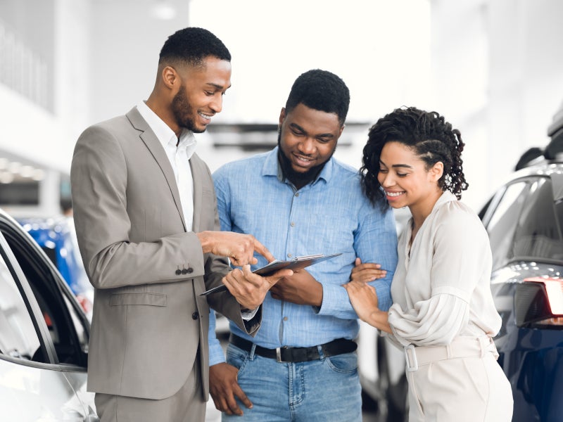Couple looking at their car options with sales representative - Al Serra Chevrolet in Grand Blanc MI