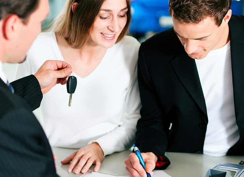 Couple signing final paperwork to get their cars to their new car - Al Serra Chevrolet in Grand Blanc MI